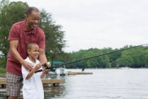 Un grand-père enseignant à son petit-fils à pêcher — Photo de stock