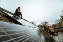 Retrato de mulher adulta média sentado no telhado da casa recém-painéis solares — Fotografia de Stock