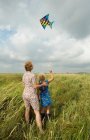 Mãe e filha voando pipa no campo — Fotografia de Stock