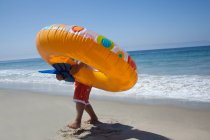 Menino carregando anel de borracha na praia — Fotografia de Stock