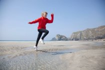 Мальчик прыгает через бассейны на пляже — стоковое фото