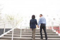Low angle full length rear view of mature couple holding hands ascending stairs — Stock Photo