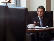 Бизнесмен, использующий мобильный телефон в кафе — стоковое фото