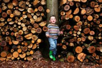 Ragazzo in piedi da tronchi di legno — Foto stock