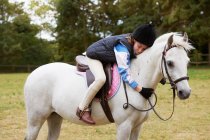 Girl cuddling her pony outdoors — Stock Photo