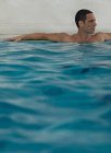 Hombre relajante en piscina infinita - foto de stock