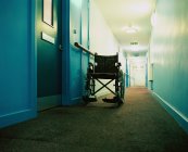Empty wheelchair in dark hospital corridor — Stock Photo