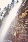 Junges Paar steht unter Wasserfall, Blick nach draußen, Tirol, Österreich — Stockfoto