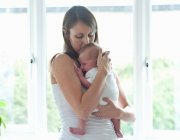 Mutter hält Säugling am Fenster — Stockfoto