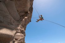 Rock climber abseiling jagged cliff — Stock Photo