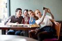 Четверо друзей фотографируют себя в ресторане — стоковое фото
