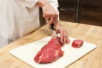 Мужчина-повар готовит мясо на коммерческой кухне, обрезанный кадр — стоковое фото