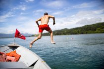 Взрослый мужчина прыгает в море с лодки, залив Нехалем, Орегон, США — стоковое фото