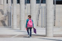 Girl carrying folder in courtyard — Stock Photo