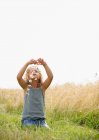 Молодая девушка делает маргаритки цепи в поле — стоковое фото