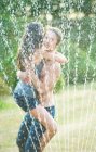Freunde umarmen sich in Sprinkleranlage — Stockfoto