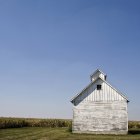 Grange en bois blanchie à la chaux dans le champ avec ciel bleu — Photo de stock