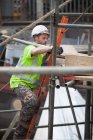 Arbeiter klettert auf Gerüstleiter in Werft — Stockfoto