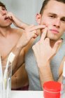 A man squeezing a spot in the mirror — Stock Photo