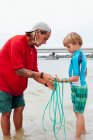 Maestro mostrando a niño cómo utilizar la red de reparto, Sanibel Island, Pine Island Sound, Florida, EE.UU. - foto de stock