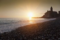 Сонце встановлює над кам'янистим пляжем — стокове фото