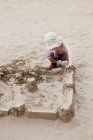 Menino edifício sandcastle na praia — Fotografia de Stock