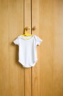 Babygro hanging on wooden wardrobe — Stock Photo