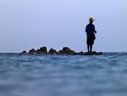 Чоловік стоїть на каменях в океані — стокове фото