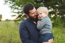 Padre che tiene giovane figlio in campo — Foto stock