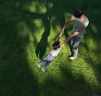 Father swinging son around, outdoors, elevated view — Stock Photo