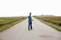 Чоловік йде по сільській дорозі — стокове фото