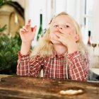 Mädchen isst Weihnachtsplätzchen in Küche — Stockfoto