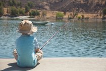 Rear view of little boy fishing by lake — Stock Photo