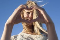 Retrato de jovem mulher fazendo sinal de coração, Breezy Point, Queens, Nova York, EUA — Fotografia de Stock