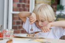 Junge isst mit Messer und Gabel im Café — Stockfoto