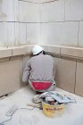 Visão traseira do trabalhador de construção sentado na frente da parede e fazendo reparação — Fotografia de Stock