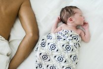 Baby boy on bed sleeping next to father — Stock Photo