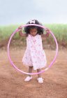 Girl playing with hula hoop on dirt road — Stock Photo