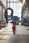 Rückansicht Arbeiter zieht Rohrleitungen an Seilwinde in Werfthalle — Stockfoto