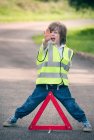 Junge spielt Verkehrshelfer auf Landstraße — Stockfoto