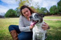 Donna matura accarezzare vecchio cane nel parco — Foto stock