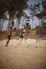 Garçons jouant au football sur la plage de sable fin — Photo de stock