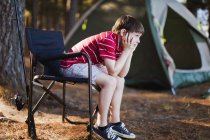 Bored boy in lawn chair at campsite — Stock Photo