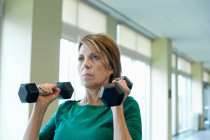 Взрослая женщина поднимает тяжести в спортзале — стоковое фото