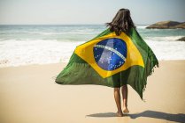 Mujer joven envuelta en bandera brasileña, Arpoador beach, Rio De Janeiro, Brasil - foto de stock