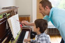 Pai ensinando filho a tocar piano — Fotografia de Stock
