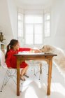 Girl feeding dog at table, focus on foreground — Stock Photo