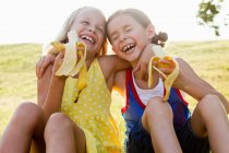 Смеющиеся девушки едят бананы на открытом воздухе — стоковое фото
