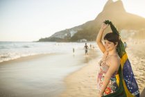 Young woman holding up Brazilian flag, Ipanema Beach, Rio, Brazil — Stock Photo