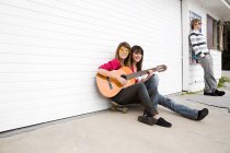 Two girls sitting on floor with guitar — Stock Photo